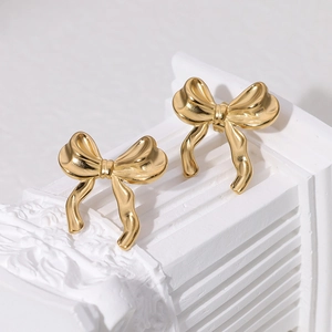 Elegant 18K gold plated stainless steel bow stud earrings on a white decorative stand