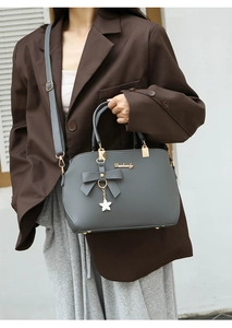 Detail of grey handbag with bow decoration, metal star pendant and Dushangly logo