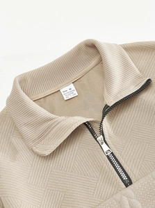 Detailed close-up of the geometric twill knit fabric and zipper on the beige pullover