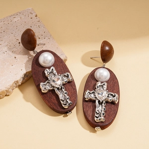 Macro detail of wood and pearl earrings with silver cross and heart crystal inlay