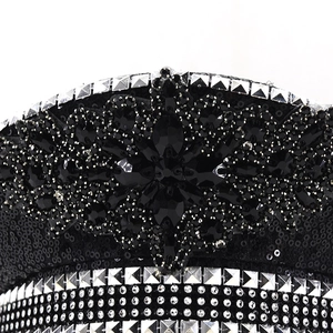 Macro detail of black sequined hat featuring crystal flower and silver metal studs