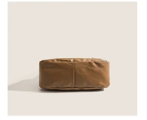 Close-up of the smooth brown faux leather texture and side stitching on the tote bag