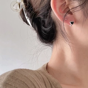Close-up of minimalist black heart stud earrings on model with silver base detail