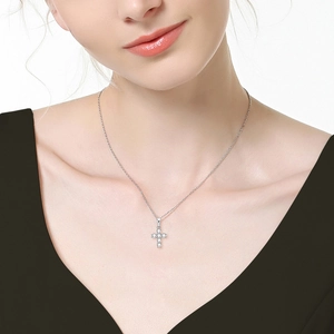 Close-up of a silver Moissanite cross pendant necklace worn by a female model
