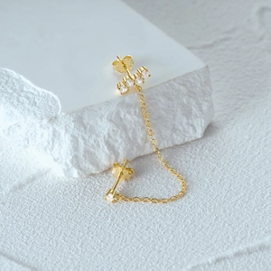 Macro shot of S925 sterling silver hallmark on gold-plated chain earrings with zircon