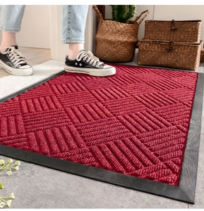 Detailed close-up of a red textured entryway mat with black non-slip rubber border