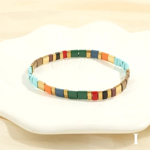 Macro detail of Bohemian Tila bead bracelet with colorful enamel blocks on a white tray