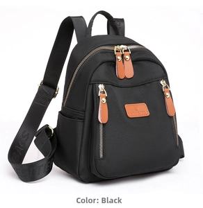 Detail of black nylon mini backpack featuring gold zippers and brown leather zipper pulls