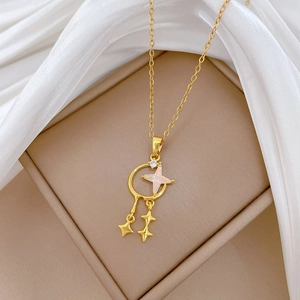 Macro detail of gold star and crescent moon pendant with opal inlay on white silk fabric