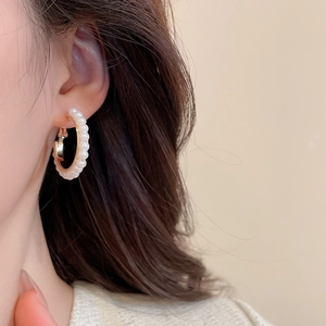 Gros plan d'un mannequin portant des boucles d'oreilles créoles dorées ornées de perles