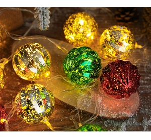 Detail view of colorful red green and gold Christmas LED globe lights on snow branches