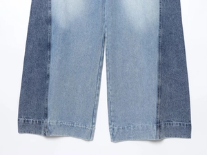 Detailed view of bicolor patchwork denim cuffs with sharp stitching and blue fabric texture