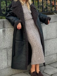 Detail of long shearling coat with leather texture and beige cable-knit dress