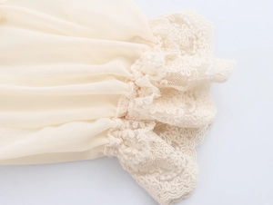 Détail de la manche en mousseline abricot avec bordure en dentelle et plis élégants