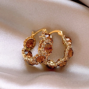 18k gold plated round earrings with champagne diamonds on beige silk fabric