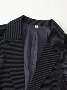 Gros plan sur un blazer noir à rayures avec broderie florale en paillettes et étiquette S