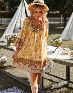 Détail d'une robe bohème jaune à fleurs avec col en V dans un cadre extérieur ensoleillé