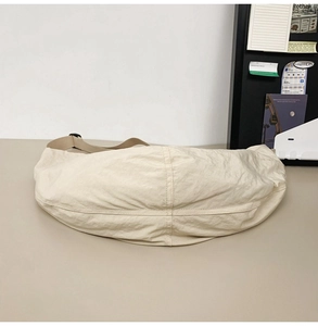 Détail d'un sac bandoulière en nylon beige avec design plissé et sangle kaki ajustable