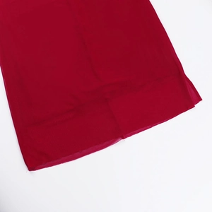 Detailed view of the red mesh fabric hemline with precise stitching on a split dress