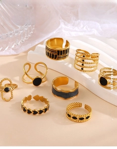 Detail of gold stainless steel rings with black enamel hearts and geometric designs