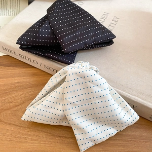 Detailed view of polka dot bow hair clips in black and white on a wooden table