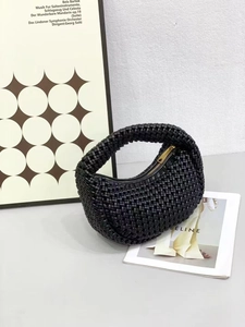 Detailed view of black hand-woven crescent bag texture with premium gold metal zipper