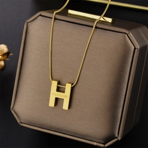 Macro view of gold H-letter necklace with Fashion engraving on brown textured gift box