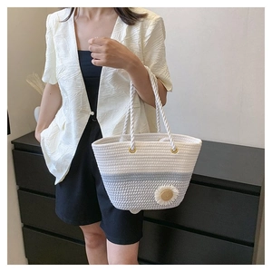 Detail of hand-woven tote bag with contrast colors and 3D floral accent held by model