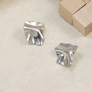 Macro detail of silver irregular crumpled texture on high-polished steel stud earrings