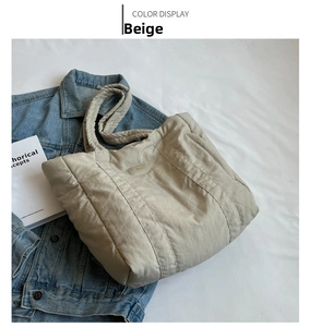Detail of soft quilted off-white tote bag with padded texture and stitched logo patch
