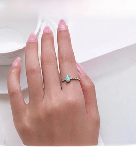 Makroaufnahme eines birnenförmigen Opalrings mit zirkonia-besetztem Silberband am Finger