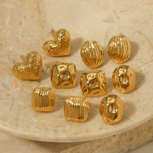 Textured gold earring set featuring heart, square and oval shapes on marble display
