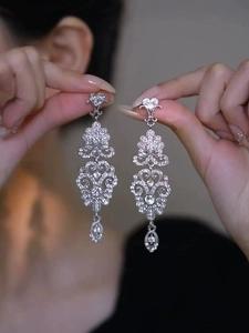 Détail de boucles d'oreilles argentées avec motifs de cœurs et pendentifs en cristal