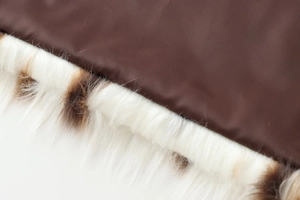 Close-up of brown woven fabric and white faux fur trim with spots on the fashion coat