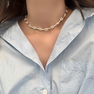 Detailed close-up of a pearl flower choker necklace on a female model neck