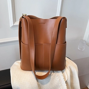 Detailaufnahme der braunen Leder-Eimertasche auf strukturiertem weißem Stoffhintergrund