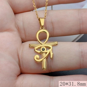 Close-up of golden Ankh cross necklace with Evil Eye zircon detail held in hand