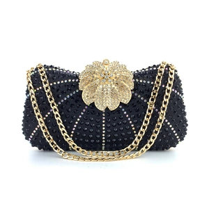 Detailed view of black evening clutch with wave-patterned rhinestones and gold flower clasp