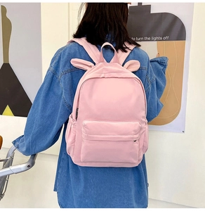 Pink student backpack with rabbit ears and side pocket in a modern setting