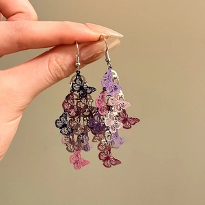 Détail rapproché de boucles d'oreilles papillon creuses avec pompons dégradés colorés