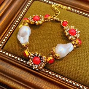 Detail of vintage gold bracelet with white pearls and red floral gemstone charms