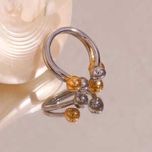 Macro shot of a two-tone silver and gold open ring reflecting on a smooth surface