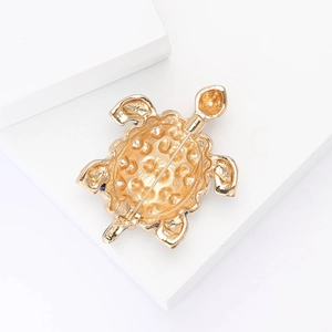 Detailed back view of golden turtle brooch showing safety pin clasp and textured metal