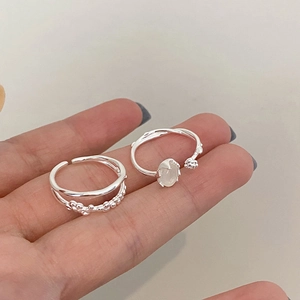 Detailed view of silver resin open rings with pearl beads and white gemstone inlay