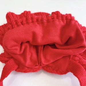 Detail of red knitted baby hat featuring warm double-layer lining and soft stitching