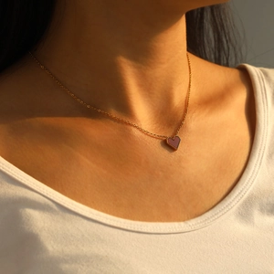 Detailed close-up of a 18k gold-plated heart necklace worn by a model in soft sunset light