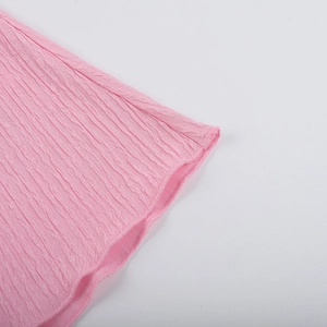 Détail du tissu seersucker rose avec texture gaufrée et coutures fines sur le bord