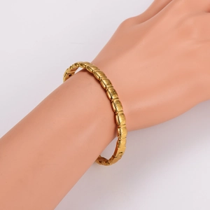 Detail showing gold stainless steel bangle with a bamboo texture on a mannequin arm
