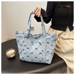 Detail of light blue corduroy tote bag featuring small black ribbon bow patterns
