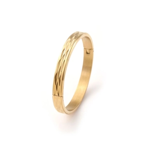 Macro detail of golden bangle showing sophisticated diamond-cut texture and hinge